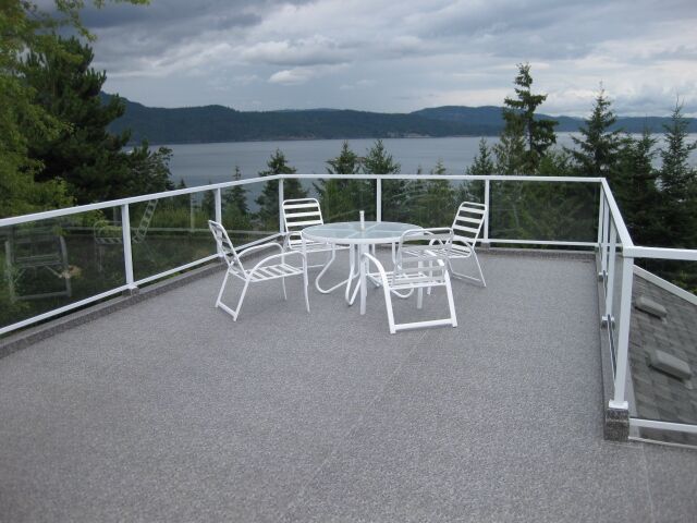 Patio furniture on newly installed waterproof vinyl decking with a lake in the background.