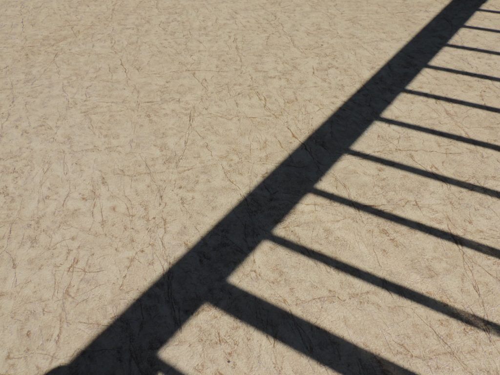 Shadow of deck railing on newly installed Econodek waterproof outdoor vinyl flooring