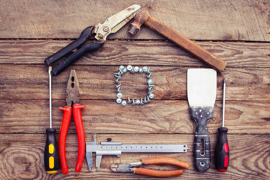 Various tools laid out on a wooden deck in the shape of a house with a window