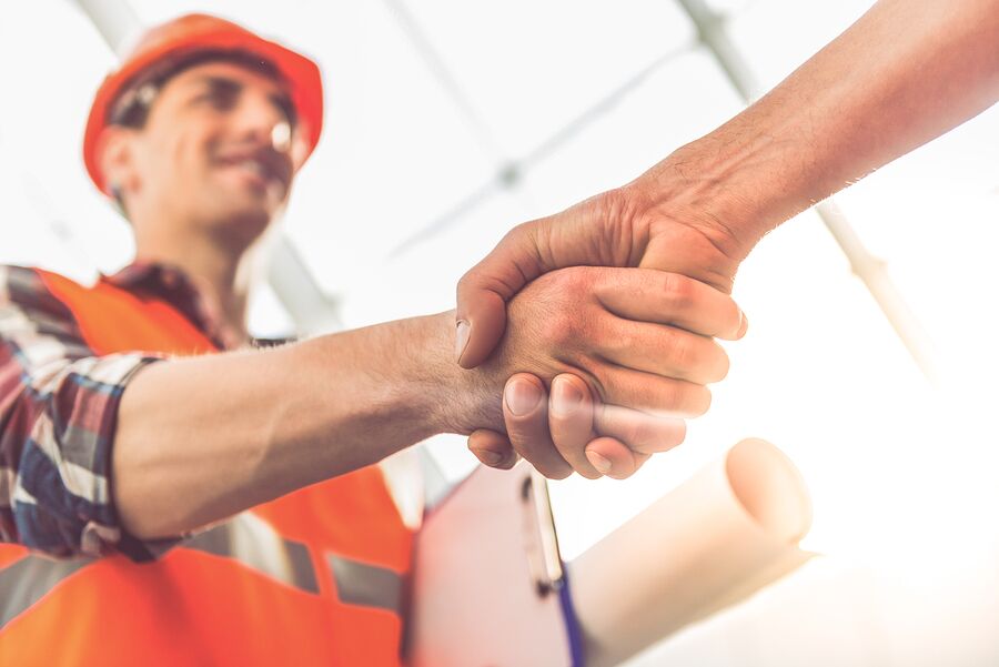 Construction contractor holding plans and shaking hands with someone