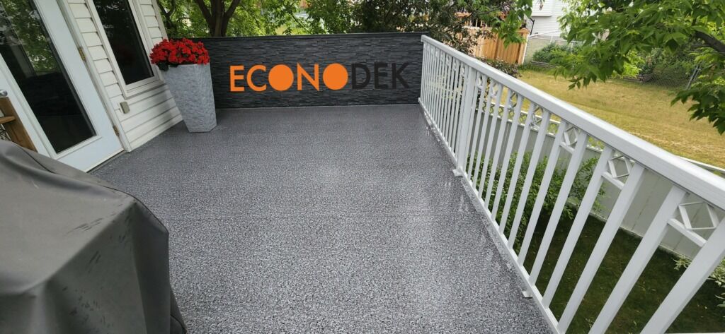 Newly installed waterproof vinyl decking on a backyard 2nd story deck with white railings.